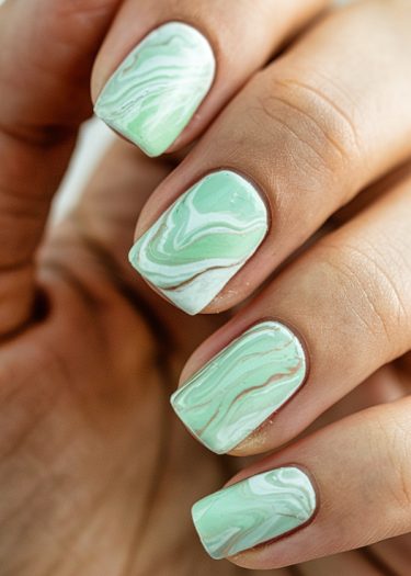 Beautiful pastel green marble nails with unique swirls, showcasing elegant and artistic nail art design.