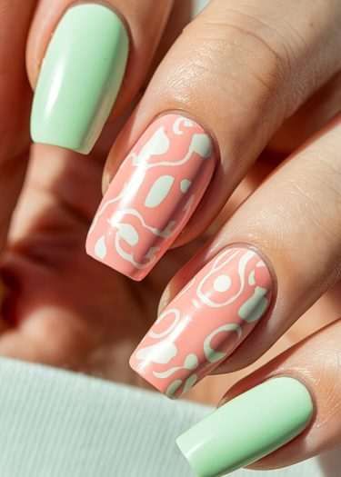 Trendy mint green and coral pink nail art with abstract designs for stylish manicures.