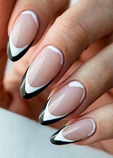 Elegant almond-shaped nails with modern French tips featuring black and white geometric designs.