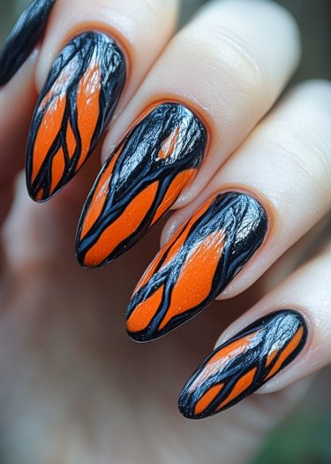 Striking monarch butterfly nail art in black and orange with intricate designs and glossy finish.