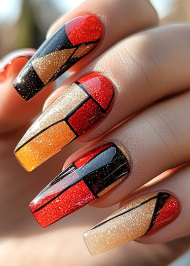 Vibrant mosaic nail art in red, orange, and gold with geometric patterns and bold black lines.