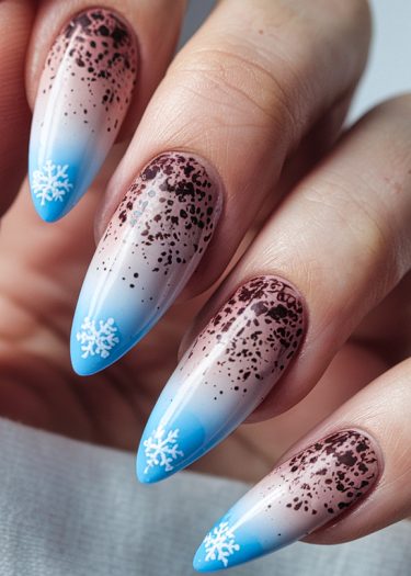 Elegant winter-themed nail art with ombre gradient and snowflake designs on almond-shaped nails.