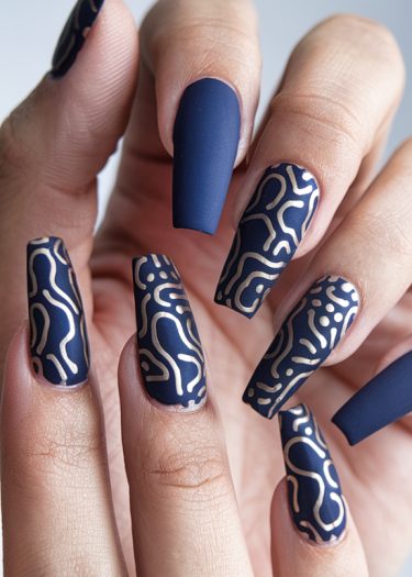 Elegant navy blue coffin nails with intricate gold patterns showcasing modern nail art design.