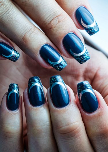 Elegant navy blue crescent nail art with glittery tips for a glamorous look.