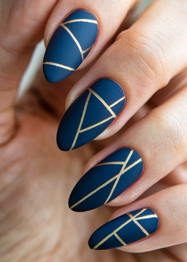 Elegant navy blue matte nails with golden geometric designs for a sophisticated look.