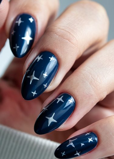 Stylish navy blue almond nails featuring silver star nail art design.