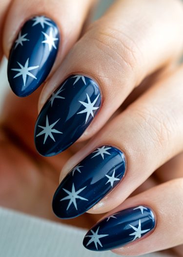 Elegant navy blue star nails with glossy finish and almond shape design.