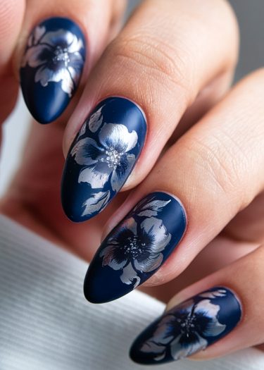 Elegant navy blue stiletto nails with floral designs for a chic nail art look.