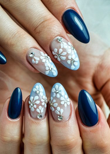 Elegant navy and pastel floral nail art design with rhinestones on almond-shaped nails.