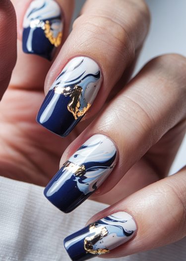 Elegant navy and white marble nails with gold accents for a luxurious manicure.