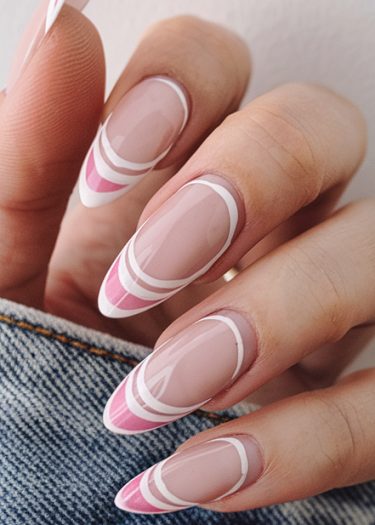 Elegant nude geometric nail art featuring intricate pink and white patterns on long almond-shaped nails.