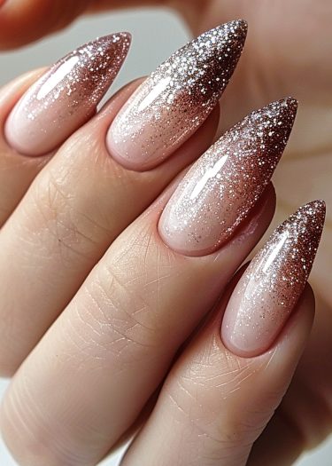 Elegant nude pink ombre glitter nails with artistic design and almond shape.