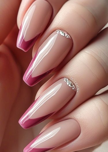 Elegant nude manicure with deep plum tips and sparkling rhinestones for a modern twist.