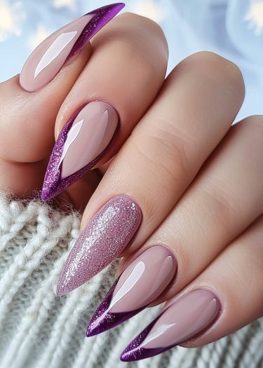 Elegant nude stiletto nails with purple glitter tips and a sparkling accent nail.