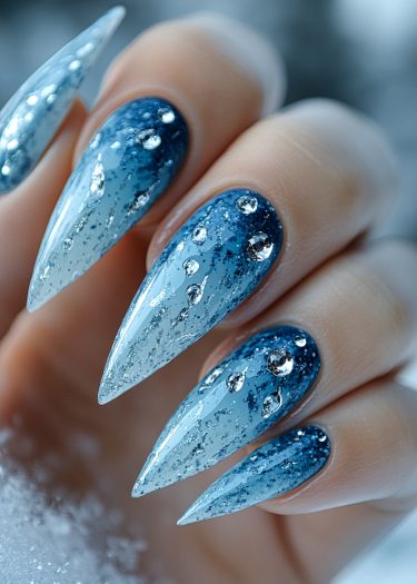 Stunning stiletto nails with ocean-blue gradient and sparkling embellishments for a luxurious winter look.