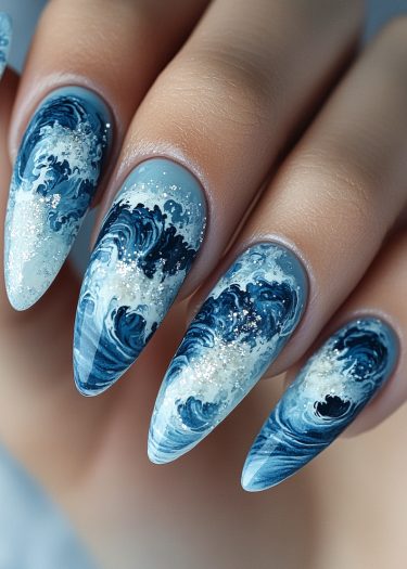 Elegant ocean wave nail art in blue tones, showcasing detailed designs on almond-shaped nails.