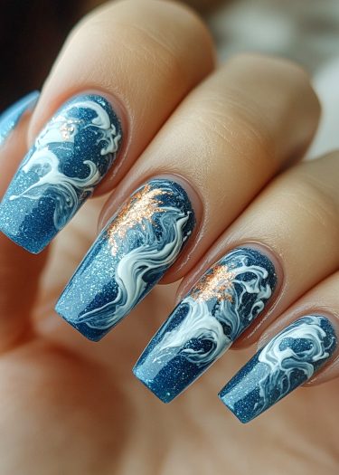 Elegant blue ocean wave nail art with intricate white swirls and shimmering gold accents.