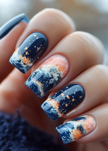 Stunning ocean wave nail art with dark blue base, white swirls, and metallic accents.