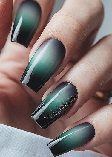 Elegant black and emerald ombre coffin nails with glitter accent for stunning nail art.