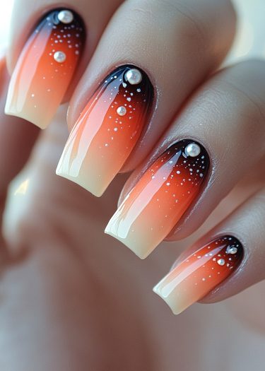 Trendy ombre orange and beige nails with white dots and pearls for elegant manicures.