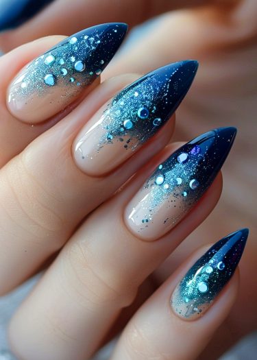 Elegant stiletto nails with blue ombre design and glitter, perfect for a luxurious manicure.