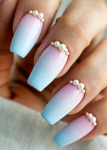 Elegant ombre pink and blue nails with pearl accents for a sophisticated manicure.