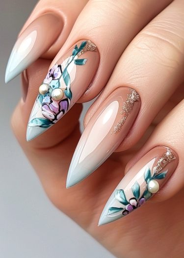 Elegant stiletto nails with ombre floral design, pearls, and glitter for stunning nail art.