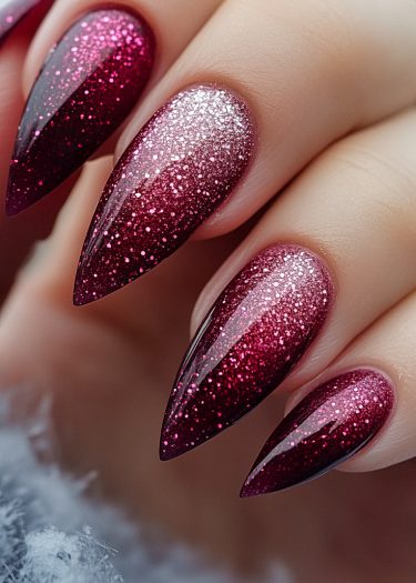 Elegant stiletto nails featuring burgundy ombre and sparkling glitter for a luxurious manicure.