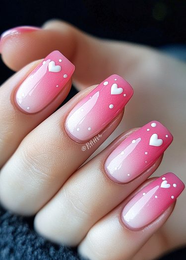 Vibrant ombre pink nail art with heart decorations for a stylish, elegant manicure.