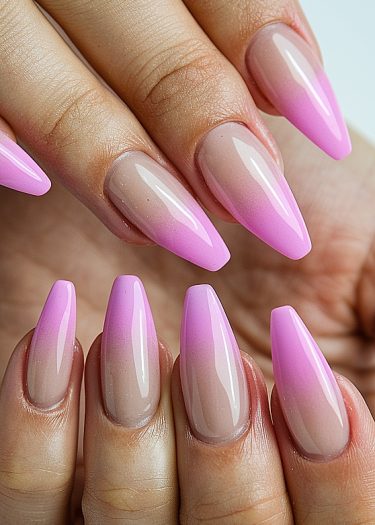 Elegant stiletto nails featuring a vibrant pink ombre gradient design and high-gloss finish.