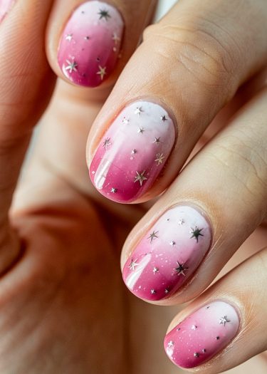 Ombre manicure design with pink gradient and star embellishments for a stylish look.