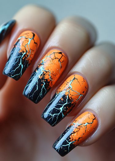 Vivid orange and black lightning nail art with glittery design for bold style.