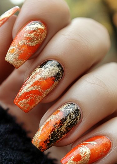 Vibrant orange and gold marble nail art with black accents for a stunning manicure look.