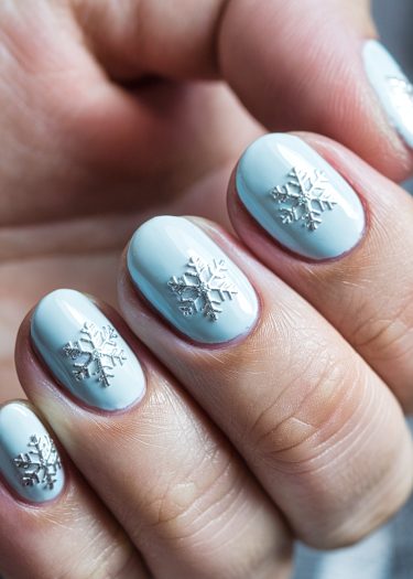 Elegant pastel blue snowflake manicure for a chic winter look.