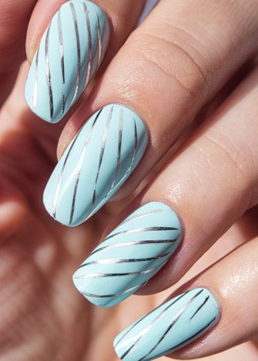 Pastel blue almond manicure with elegant silver stripes for a chic, modern nail design.