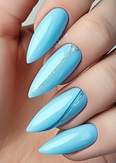 Elegant light blue almond-shaped nails with a silver accent, showcasing modern nail art sophistication.