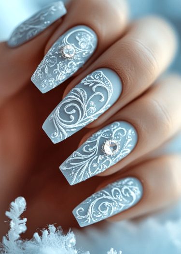 Elegant pastel blue nail art featuring intricate white filigree and sparkling rhinestones.