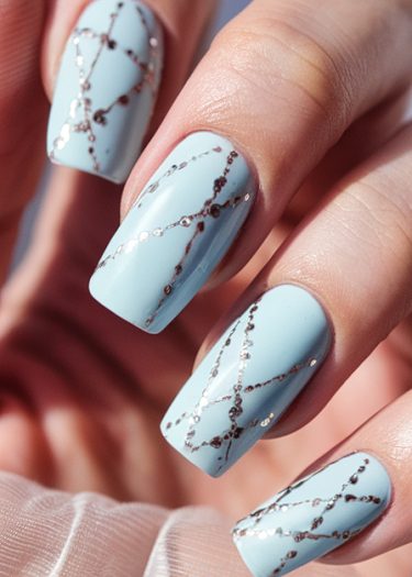 Pastel blue nail art featuring geometric designs and silver accents for an elegant manicure.