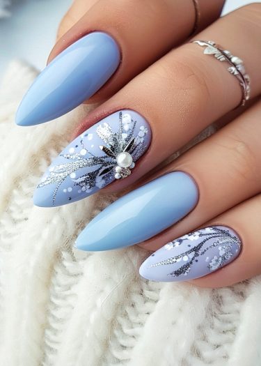 Elegant light blue stiletto nails with intricate winter-themed nail art and stylish jewelry.