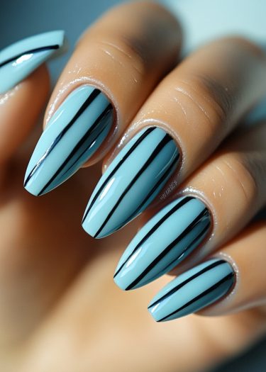 Elegant pastel blue nails with striking black stripes for a modern nail art look.