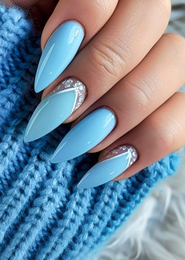 Chic pastel blue stiletto nails adorned with silver accents and rhinestones for a stylish look.