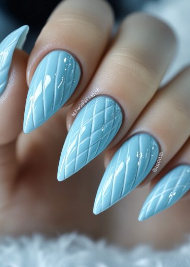 Elegant pastel blue stiletto nails with intricate quilted design and glossy finish.