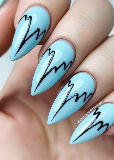 Stylish pastel blue stiletto nails with artistic black outline design and glossy finish.