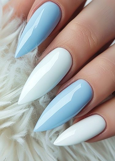 Elegant stiletto nails in pastel blue and white on a plush white background.