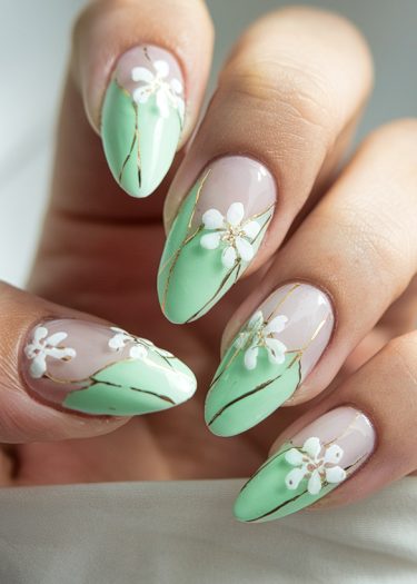 Elegant mint green almond nails with floral designs and golden accents.