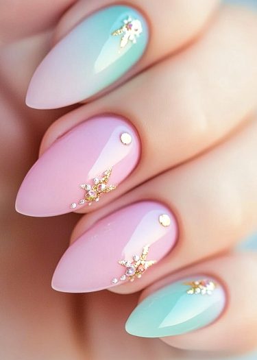 Elegant pastel gradient nails with gems and gold leaf embellishments for a sophisticated look.