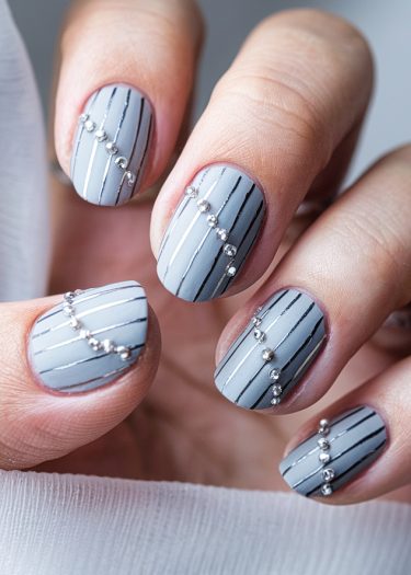 Elegant pastel blue nail art with black stripes and silver rhinestones for a chic look.