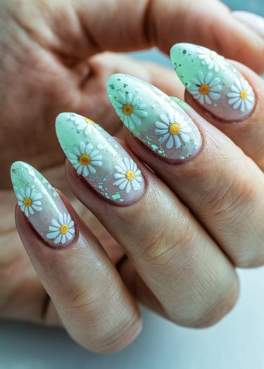 Elegant mint green daisy nail art featuring intricate floral designs on almond-shaped nails.