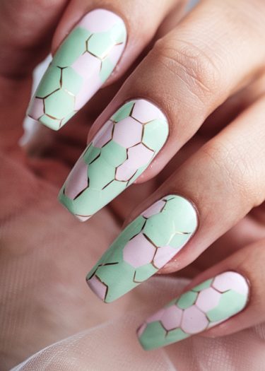 Elegant pastel hexagon nail art with gold accents on glossy almond-shaped nails.