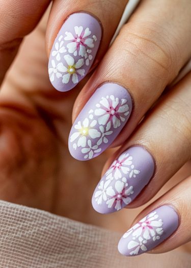 Elegant pastel lavender floral nails with intricate white daisy designs and accents.